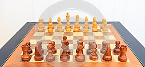 Wooden chess board with pieces on it. Leather frame, close up view, details, white background.