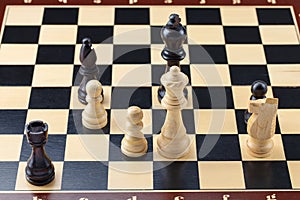 Wooden chess. Chess pieces are located on a chessboard. Black checkmate and win. A chessboard stands on a white background. Close-