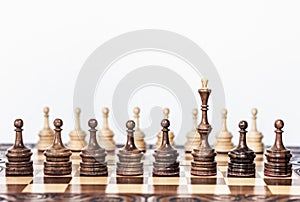Wooden chess pieces on a chessboard, black queen and white pawns on the background, leadership retro concept