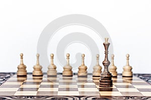 Wooden chess pieces on a chessboard, black queen and white pawns on the background, leadership retro concept