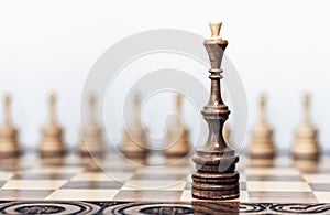 Wooden chess pieces on a chessboard, black queen and white pawns on the background, leadership retro concept
