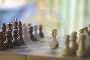 Wooden chess pieces on the chessboard with blurred color background