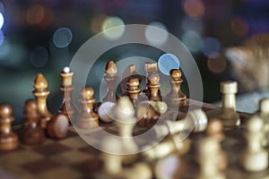 Wooden chess pieces on the chessboard with night lights abstract background