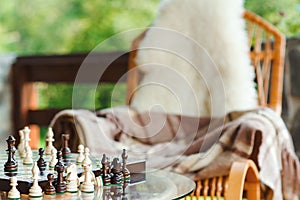 Wooden chess pieces on chessboard outdoor at the sunny day, at terrace house.