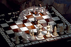 Wooden chess pieces on a wooden chessboard outdoor at the sunny