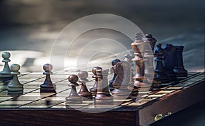 Wooden chess pieces on a wooden chessboard outdoor at the sunny