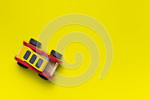 Wooden children`s toy red fire truck on yellow background flat lay top view. Kids natural eco toys. Developing toys, game. Specia