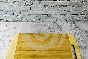 Wooden chopping board on concrete table and brick wall