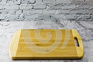 Wooden chopping board on concrete table and brick wall
