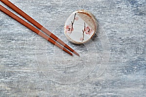 Wooden chopsticks and chopstick rest on rustic wooden background. Top view.