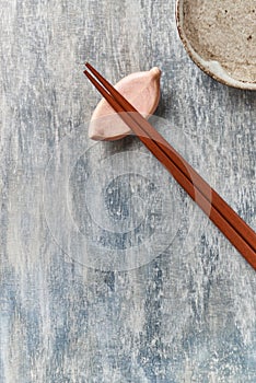 Wooden chopsticks and chopstick rest on rustic wooden background. Top view.