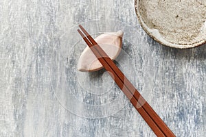 Wooden chopsticks and chopstick rest on rustic wooden background. Top view.