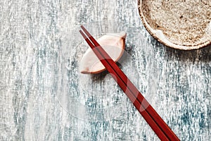 Wooden chopsticks and chopstick rest on rustic wooden background. Top view.