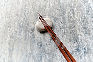 Wooden chopsticks and chopstick rest on rustic wooden background. Top view.