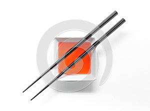 Wooden chopsticks over sweet and sour sauce bowl isolated