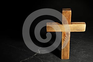 Wooden Christian cross on black slate table against background, above view with space for text. Religion concept