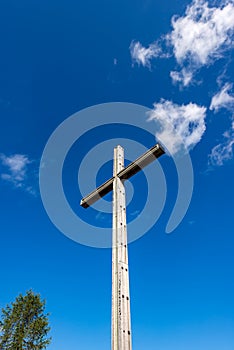 Wooden Christian cross on blue sky with clouds