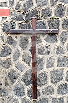 Wooden christian cross on a grey stone wall