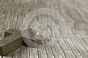Wooden Christian cross on a rustic wooden surface, sepia toning photo
