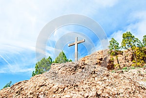 Wooden Christian cross towers on a stone rock on the background of a blue sky with clouds