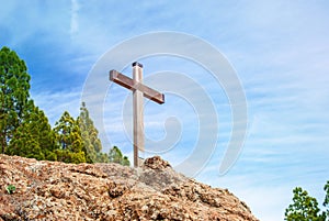 Wooden Christian cross towers on a stone rock on the background of a blue sky with clouds