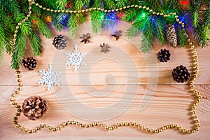 Wooden Christmas background with spruce branches, cones, garlands and decorations
