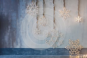Wooden christmas decoration for the walls. Glowing snowflakes with garland lights on gray concrete background. Christmas