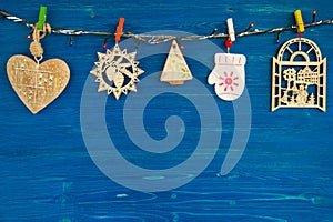 Wooden Christmas decorations and Christmas lights on the blue wooden background.