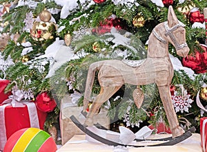Wooden Christmas rocking horse next to a decorated Christmas tree.