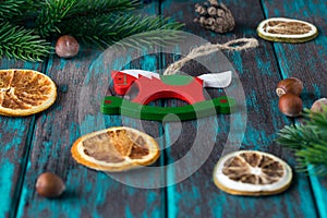 Wooden christmas toy with spruce branches, citrus dried slices, hazelnuts on rustic wooden desk.