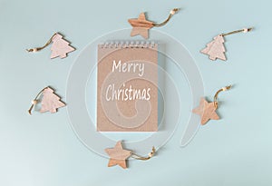 Wooden Christmas toys Christmas trees and stars around a Notepad with the inscription happy Christmas, template, top view, flat