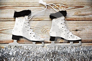 Wooden Christmas tree toy Skates with snowflakes, tied with rope, on white tinsel imitating ice. Wooden background. Creative  New