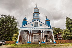 Wooden church Nuestra Senora Del Patrocinio in Tenaun on Chiloe with a white facade, blue stars and steeples and white photo