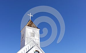 Wooden Church Steeple with Cross. White Old Church, Blue Sky On Background. Copy Space For