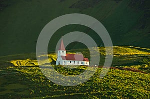 Wooden church on top of green hill at sunrise, Vik, Iceland