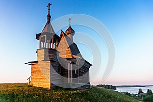 Wooden church on the top of the hill. Vershinino village sunset view. Arkhangelsk region, Northern Russia.