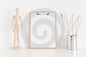 Wooden clipboard mockup with workspace accessories on a white table