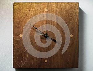 A Wooden Clock Against a White Wall