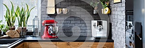 Clock on black brick wall in trendy kitchen with red kitc