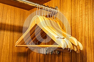 Wooden cloth hangers in the wardrobe rail for clothes organization