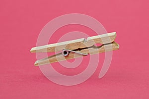 Wooden cloth peg over pink background