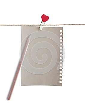 Wooden clothespin with heart shape design and brown paper sheet for valentine concept isolated