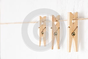 Wooden clothespins with a metal spring hang on a rope on a white background. selective focus