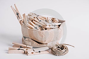 Wooden clothespins in paper bag with rope on white background. Place for your text