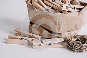 Wooden clothespins in paper bag with rope on white background. Place for your text