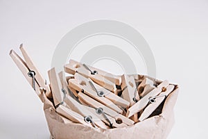 Wooden clothespins in paper bag with rope on white background. Place for your text