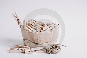 Wooden clothespins in paper bag with rope on white background. Place for your text