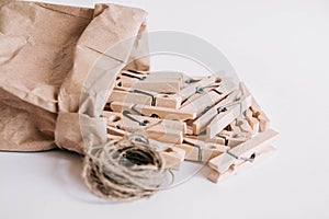 Wooden clothespins in paper bag with rope on white background. View from above. Place for your text