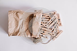 Wooden clothespins in paper bag with rope on white background. View from above. Place for your text