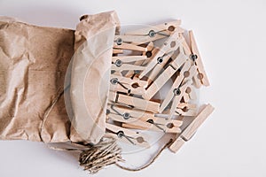 Wooden clothespins in paper bag with rope on white background. View from above. Place for your text